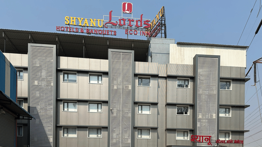 The facade of 'Shyanu Lords Eco Inn Airoli' with the signboard attached on the roof under the blue sky.