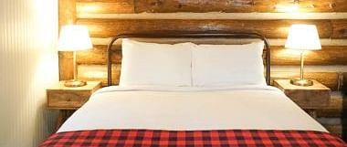 A room with a double bed and side tables with night lamps placed on it -Shaver Lake Village Hotel.
