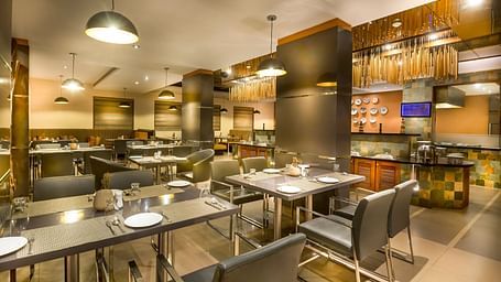  Modern restaurant interior with dark wood accents, leather chairs, and ambient lighting.