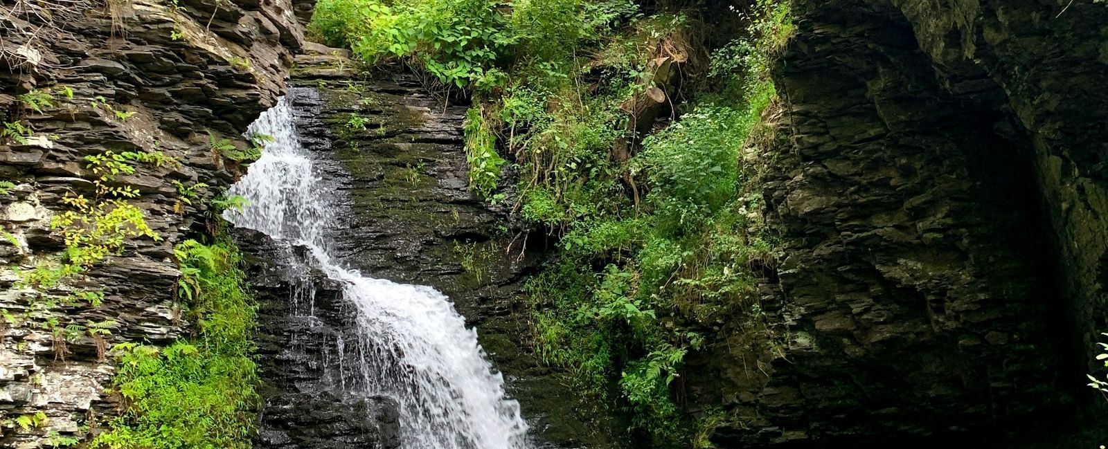 Manjehalli Falls in Sakleshpur, Karnataka, showing cascading waterfall with surrounding rocks and greenery.