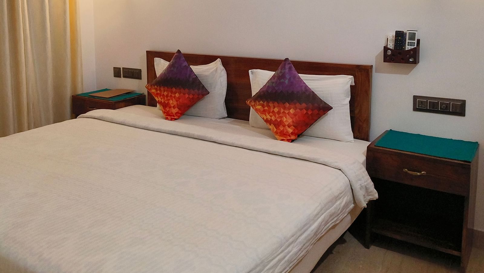 Another view of a double bed with two colourful pillows in 103 room at Ananda Holiday Home, Wayanad 3