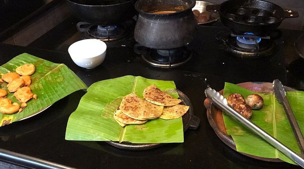 image of food plated on banana leaves with three black earthen pots on the stove at Hoysala Village Resort, Hassan