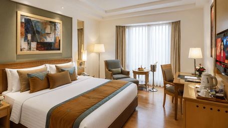 Elegant king room with warm interiors and work desk at Eastlynn Collections HUDA City Centre, Gurugram.