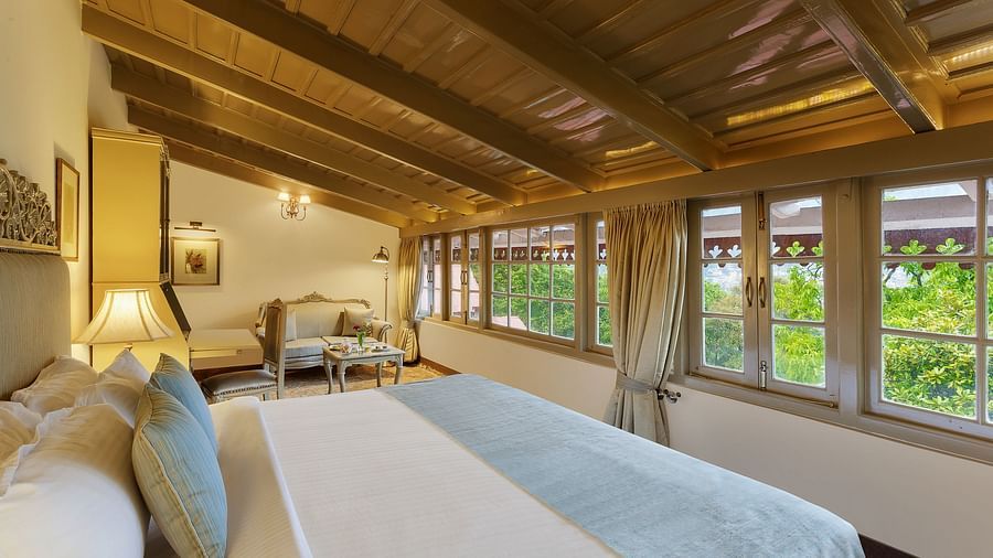 Side view of a room with a bed, sloped roof and glass windows - the naini retreat, nainital.