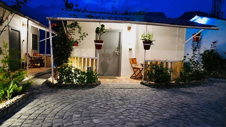 facade image of the deluxe room exterior during the night with stone pathway in front of it - The Tattva Boutique Resort