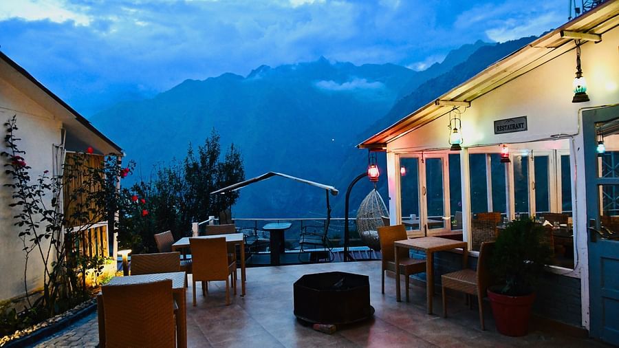 image of the outdoor seating area at the tattva, joshimath with beautiful mountain landscapes in the background on a late evening