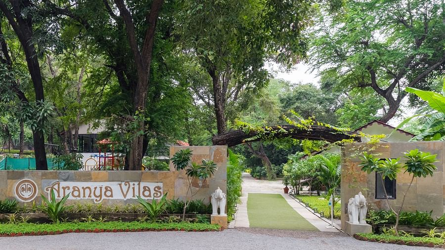 exterior image of the resort featuring the logo of aranya vilas and the serene lush greenery of the property within the perimeter