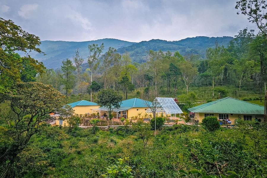 long shot view of Ibex Stays & Trails, Valparai (Mistly) with mountain background 