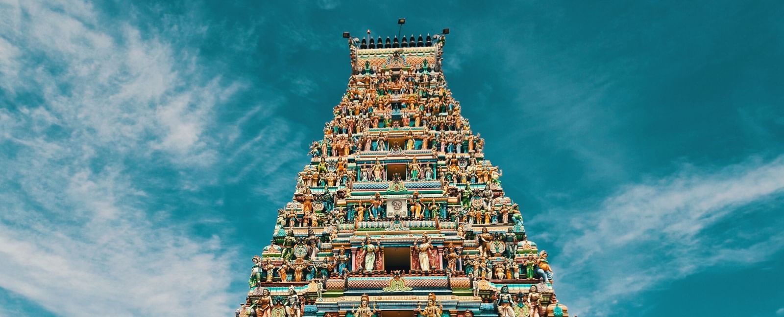A temple with intricate carvings on its roof and two hindu deities on either side of the entrance.
