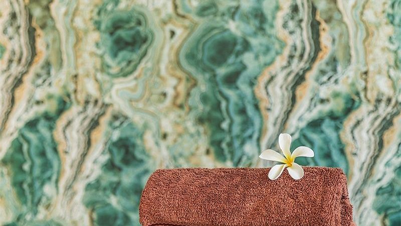 Rolled towel placed on a black stool in front of a marble wall at Karma Chalets.