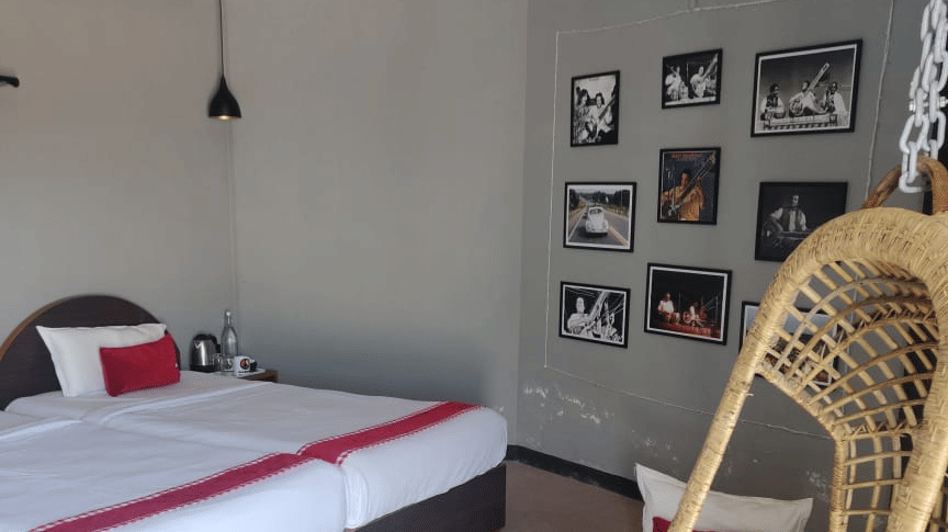 A room at Woodstock Farmhouse, Shillong, featuring a large bed, spreads, pillows, swing, and wall art.