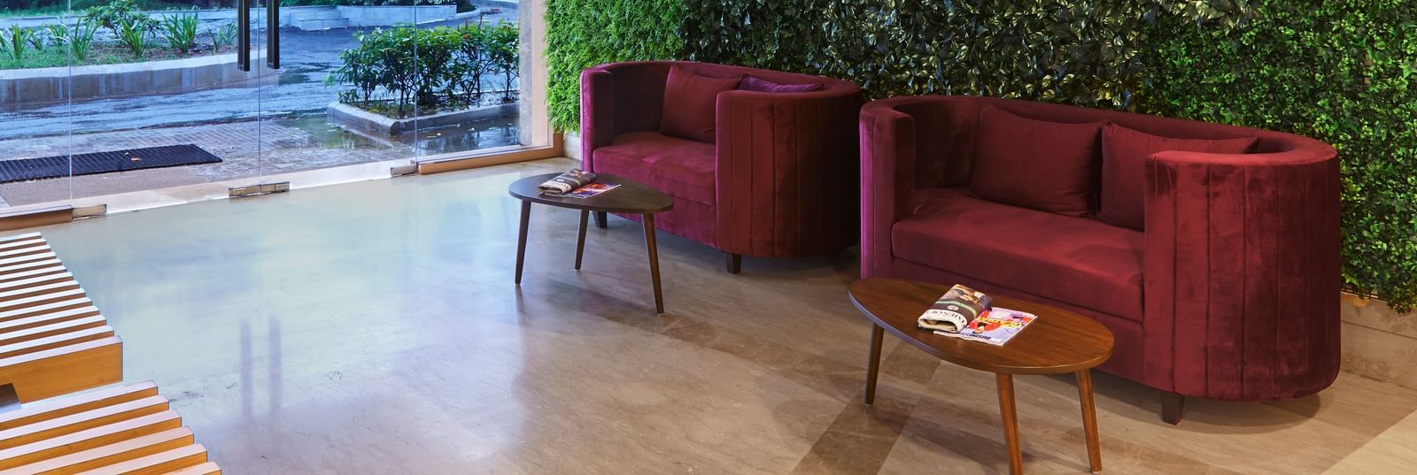 The main entrance and reception area of Monday Hotels Mahape, Navi Mumbai, with a vertical garden and contemporary furniture.