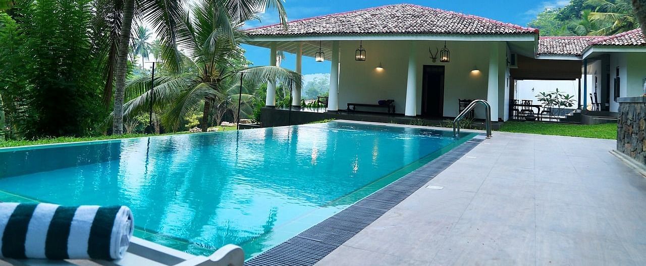  A stunning outdoor pool surrounded by tropical plants and palm trees, offering a tranquil and relaxing setting for guests.