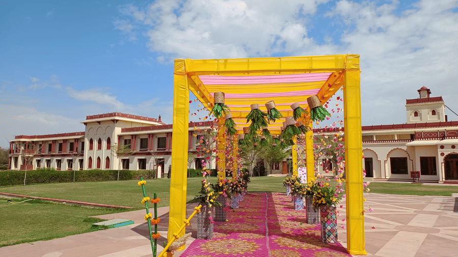 Decorated entrance to The Ummed Jodhpur, with a colorful canopy, flower arrangements, and a view of the palace in the background.