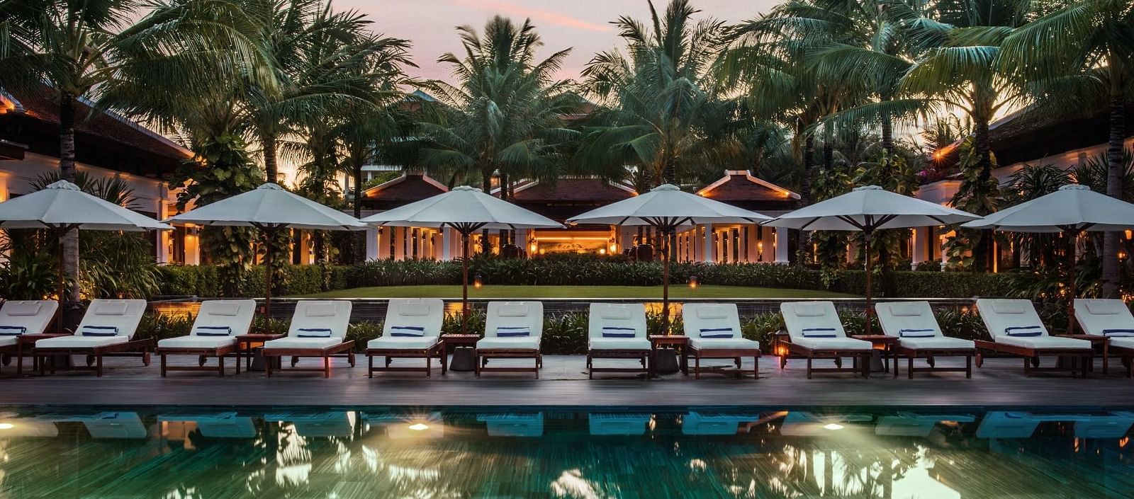beach chairs and umbrellas in front of a pool