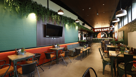 A Casual dining area of Effe Cafe at Papaya Tree Hotels featuring greenery accents, modern seating, and a relaxed atmosphere for guests.