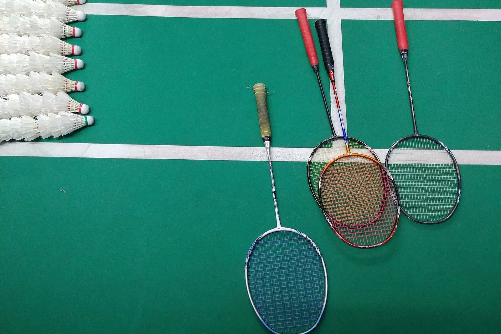 Two rackets and a shuttlecock on a badminton court, ready for a game.
