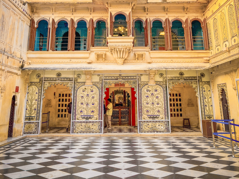 Ornate courtyard entrance of Udaipur City Palace with a checkered marble floor.