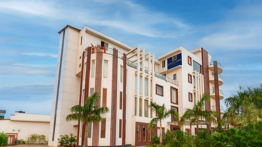 Exterior view of the multi-story resort building under a bright blue sky - Eastlynn Resort, Rishikesh