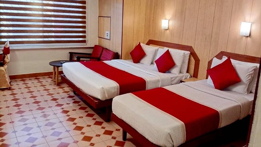 Room with a single bed, a double bed, and a seating area at Hotel Swagath, Bangalore