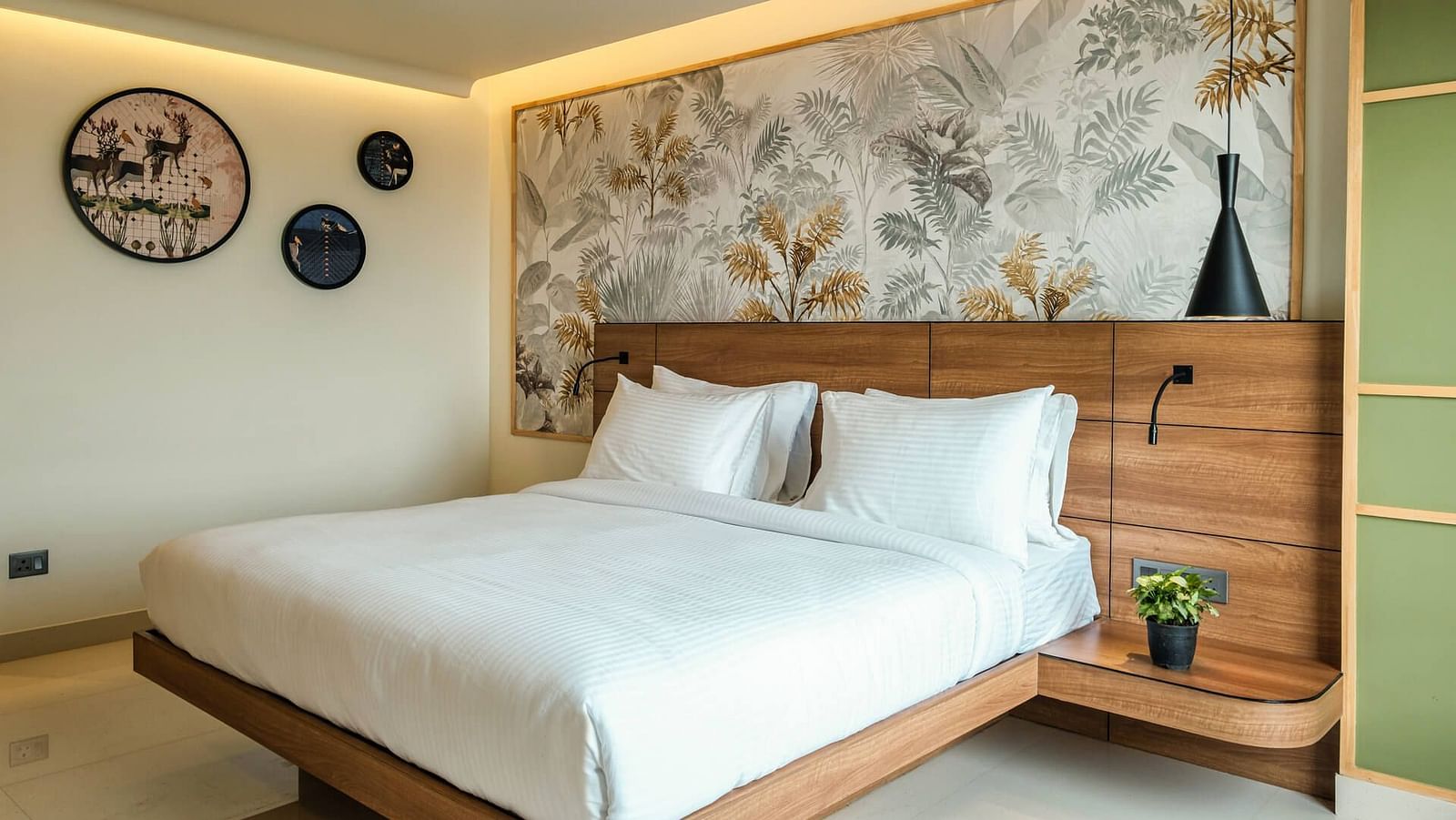 A spacious room at Indie Stays, Jaipur, featuring a large bed with a wooden headboard and warm lighting.