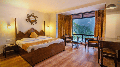Spacious Deluxe Lake Facing Room with a cosy bed, two chairs and a table at Himalaya Hotel, Nainital