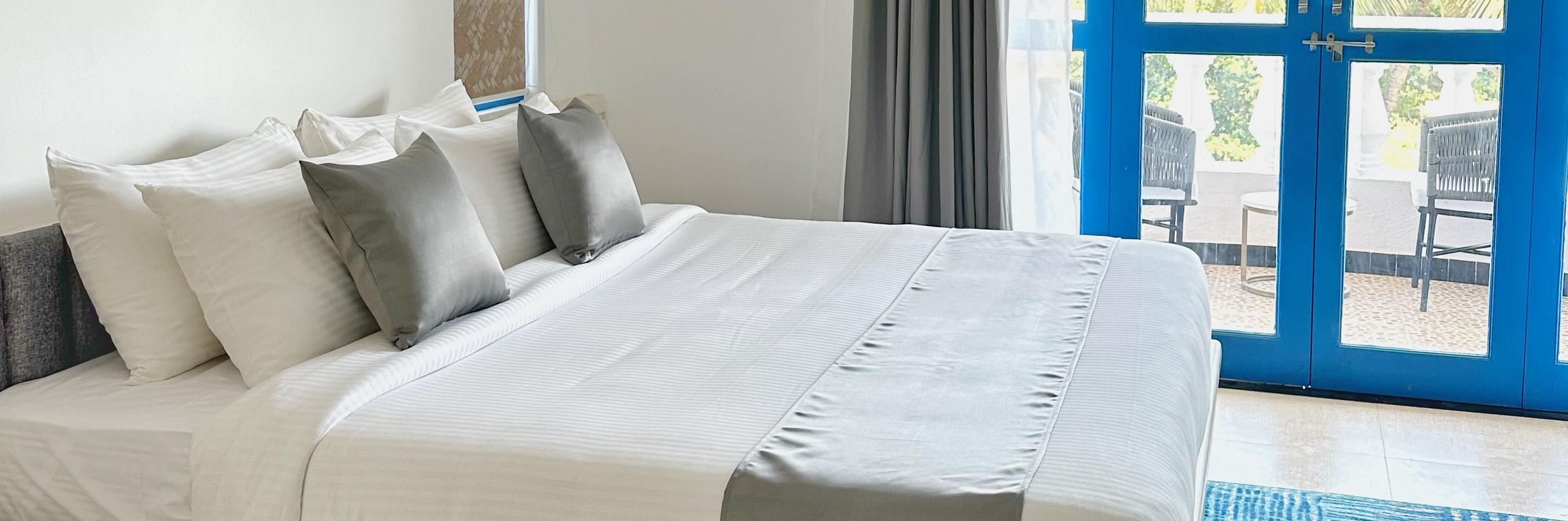 A king bed with blue door to the balcony inside one of the rooms at Azalea By Stone Wood Premier, Orlim