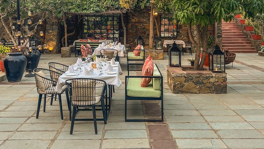 An image of an outdoor seating at the hotel with trees around - Utsav Camp Sariska