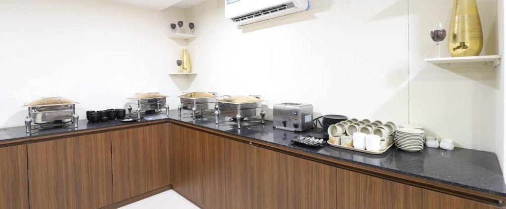 The buffet counter at Aranaya Restaurant at Pravasa Stay, Ahmedabad (Alba Premier), with a wall-mounted split AC above it.