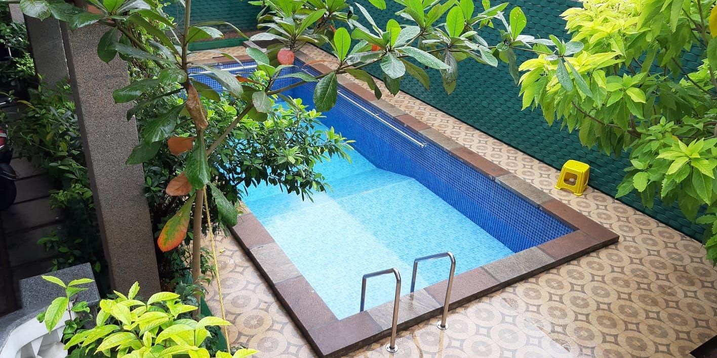 Image of a an outdoor swimming pool with trees on the side at Villa Serenity Le Sejour Pondicherry.