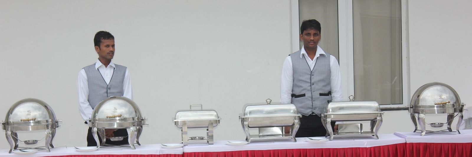 Two man standing behind a bufffet table at Swathi Hall at Hotel Green Apple