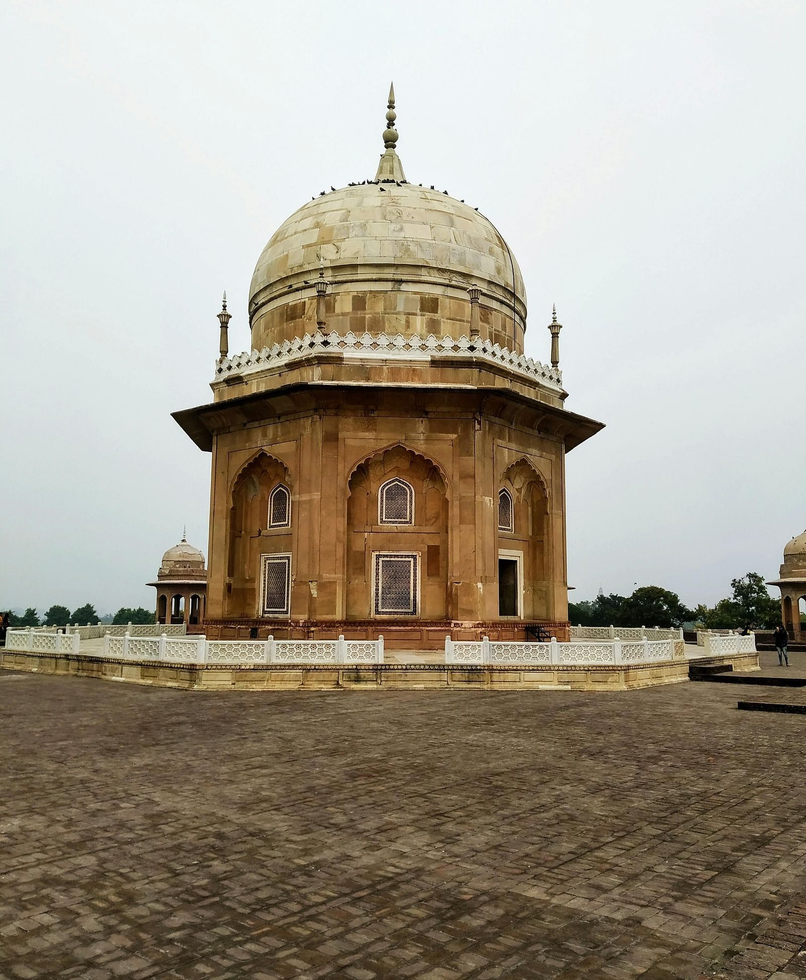 A spherical dome of an ancient sandstone building set against an overcast sky