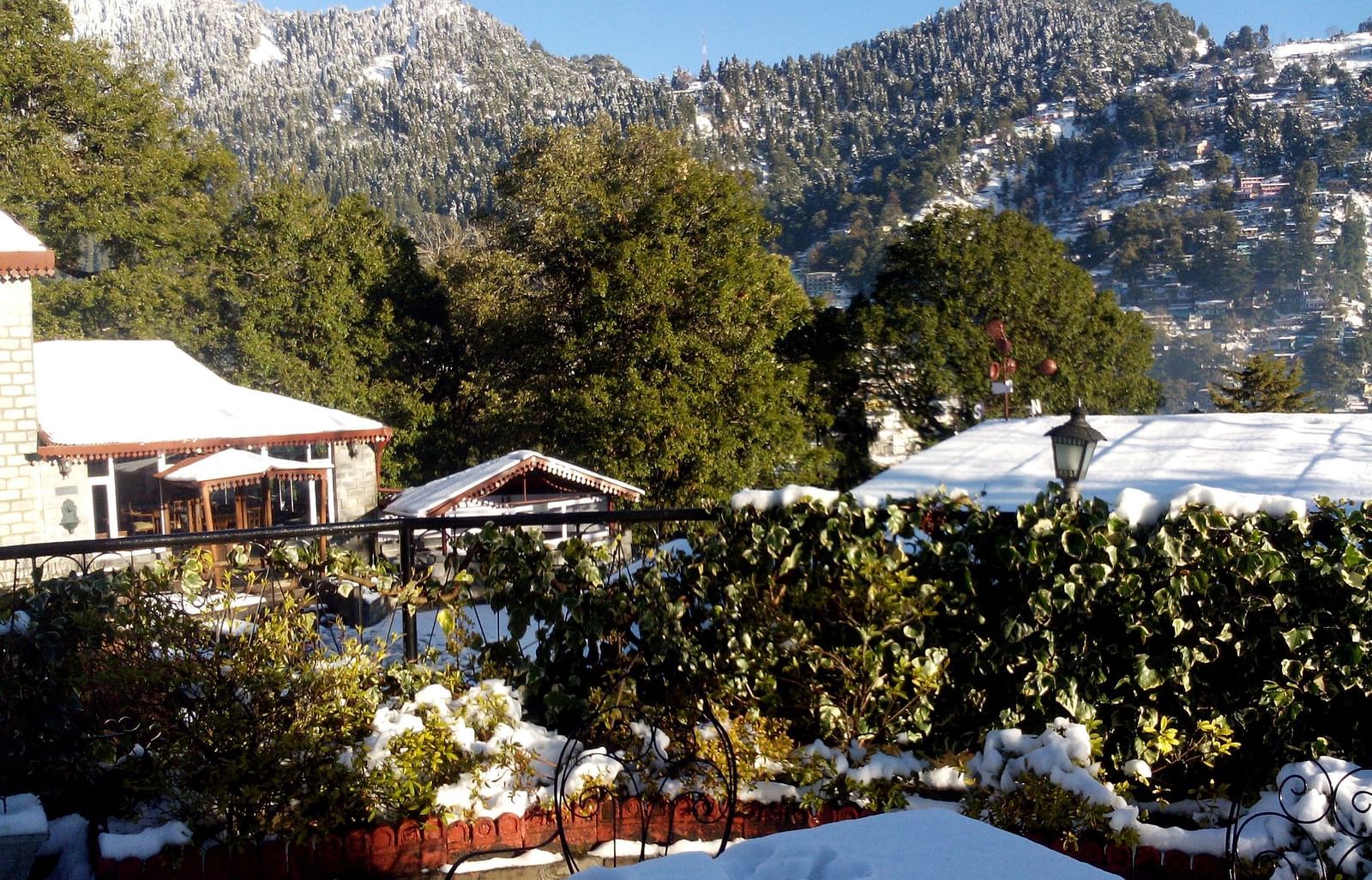 Image of outdoor seating, with a few buildins covered with snoew and snow-capped mountains in the background.