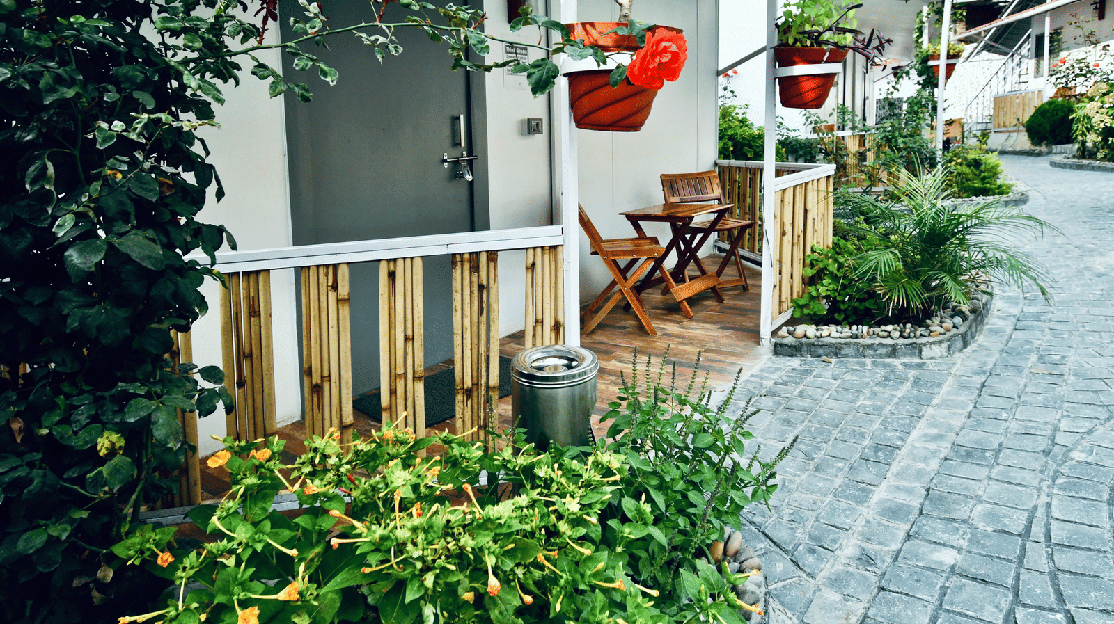 image of a porch lined with beautiful green plants with an outdoor seating area - The Tattva, Joshimath