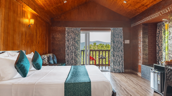 A spacious bedroom with wood panelling, a large bed, and glass doors.