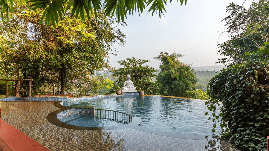 A swimming pool with a white statue at the edge, surrounded by trees.