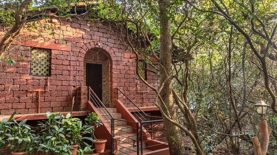 Stone steps leading up to a red stone building nestled in the trees.