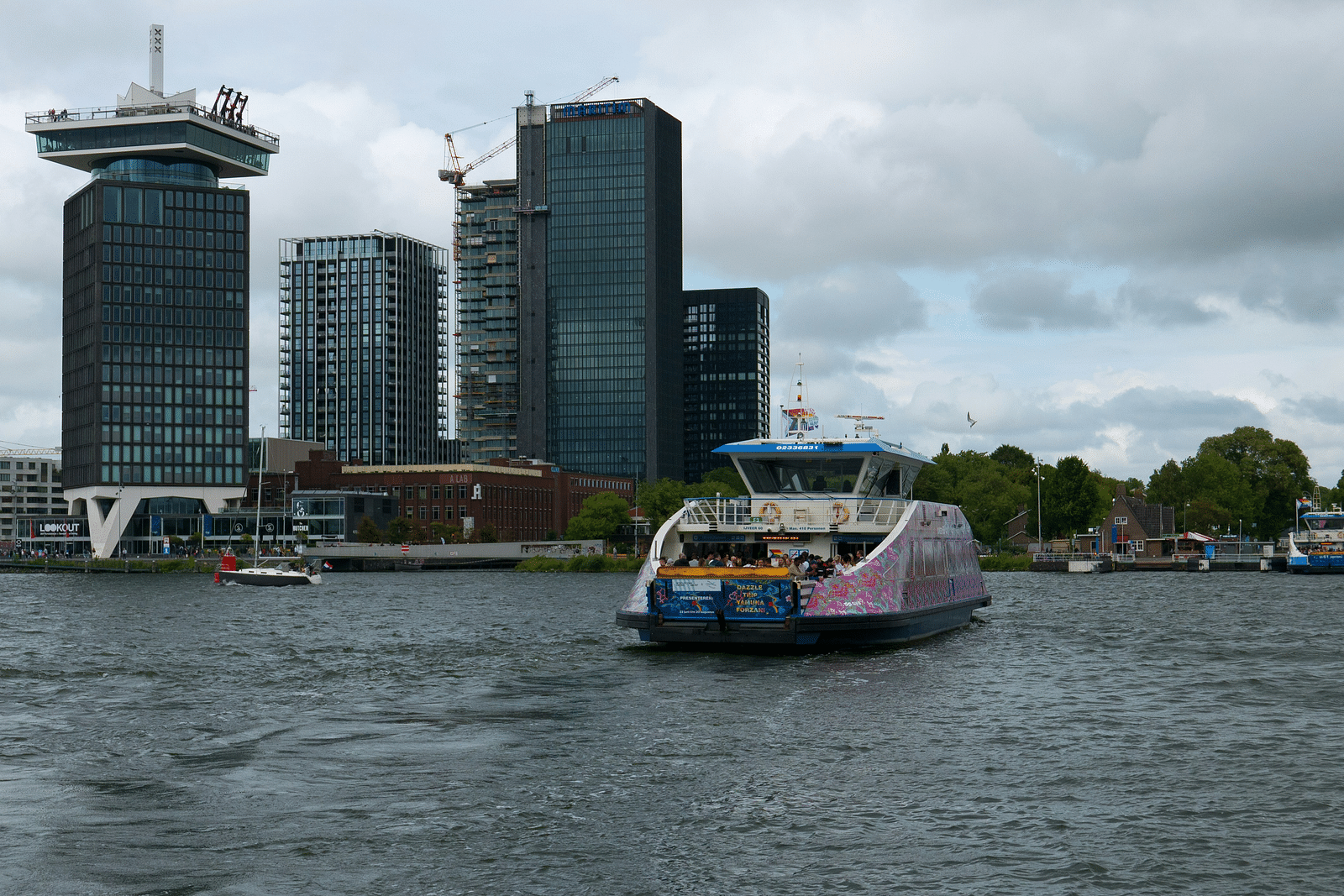 A ferry travelling on a waterbody with buildings in the background