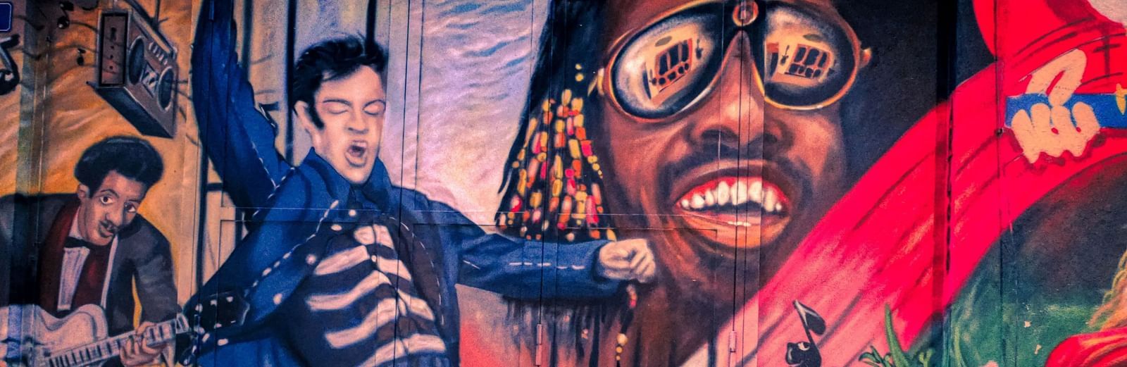 A vibrant mural depicts stylized figures, including one with glasses and a shocked expression, in a dynamic scene.