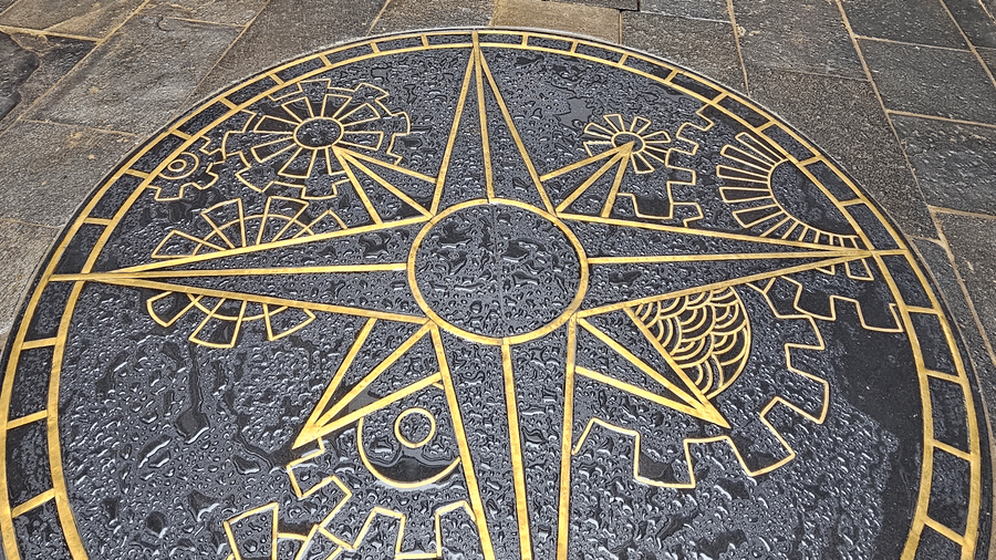 A large, circular brass mandala medallion set into the dark slate flooring of an upscale heritage hotel lobby in Bhaktapur, Nepal.