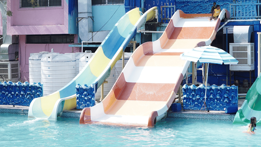 A large, blue and white water slide is emptying into a pool under a covered structure.