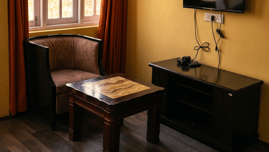 Imperial Suite at Orsino Khangri Karpo Retreat & Spa, Lachung  featuring a dark wood desk with a flat-screen TV, arm chair, and a matching coffee table.