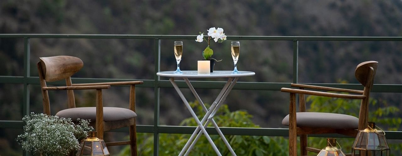An image of a seating area at a patio with drink and candles | Avalon Cottages, Kanatal