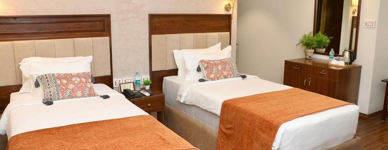 Classic Twin Room at Nalapad Hotel Bangalore International featuring two neatly made single beds with warm-toned decor, a vanity area, and modern amenities.