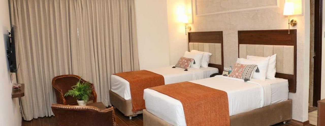 A Classic Twin Room at Nalapad Hotel Bangalore International with two beds and chairs.