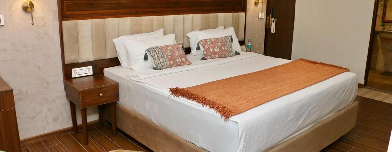 A neatly made bed with white linens and decorative pillows of Luxury Junior Suite at Nalapad Hotel Bangalore International.