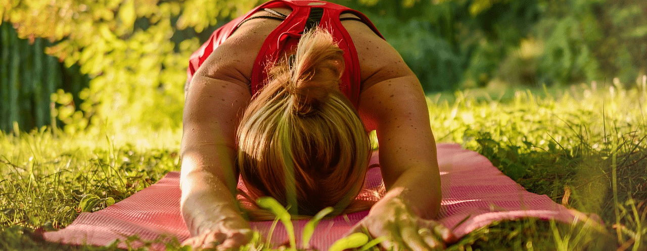 An image of a woman doing yoga in a garden filled with trees 