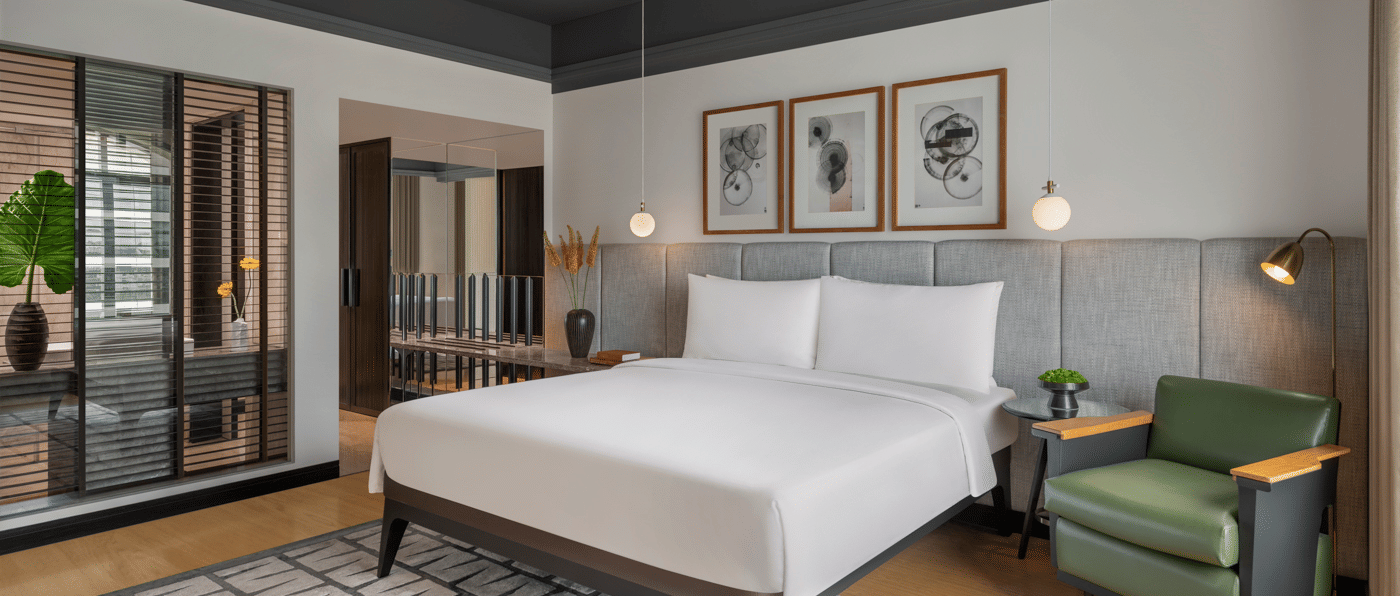 Bedroom with bed, green chair, and wall art at The Raintree, St. Mary’s Road.