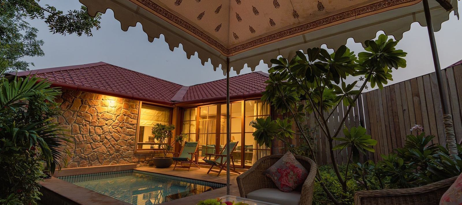 An outdoor seating area with a swimming pool in the corner at Surpura Bagh.