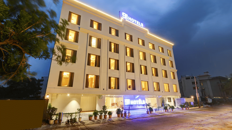 Side-angle view of the facade of Hotel 91 Privé, Gurugram, with a cloudy dark sky in the late evening time in the background.